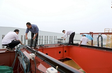 Technical staff inspecting electrical assembly of the cabin, debugging anti-sway program of the crane